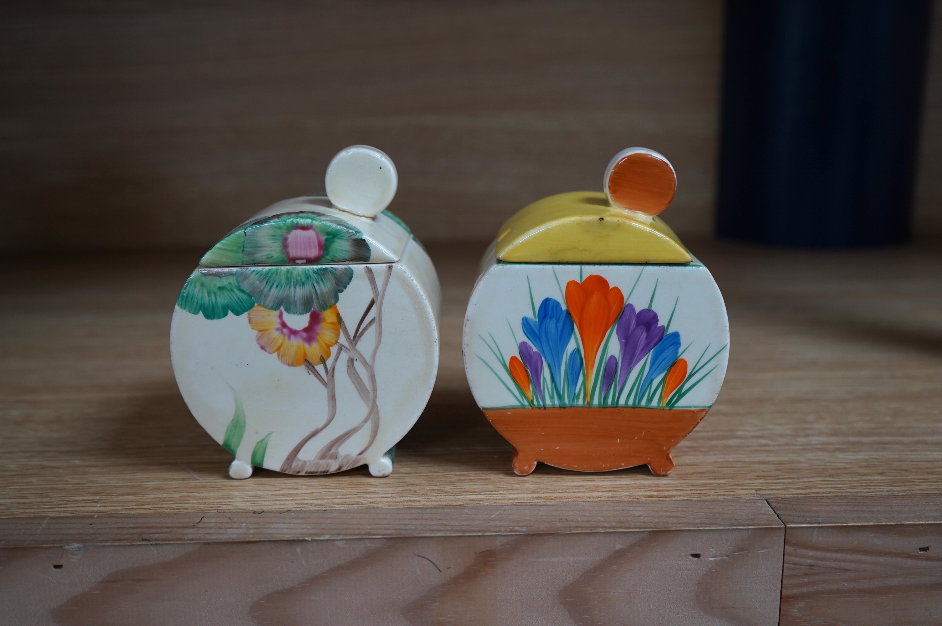 Two Clarice Cliff drum shaped preserve pots and covers, one in Crocus pattern and the other in Viscaria pattern. Condition - good